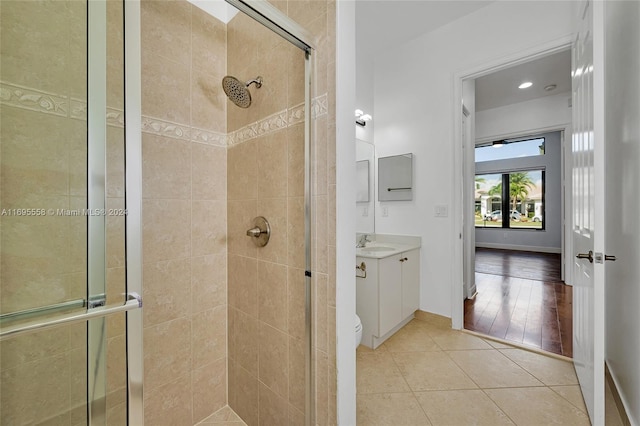 bathroom featuring wood-type flooring, vanity, toilet, and a shower with shower door