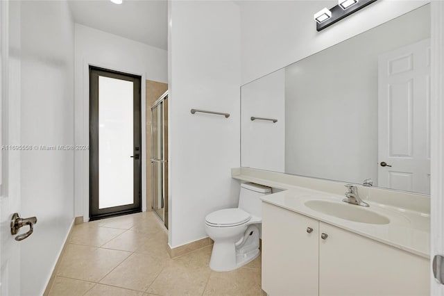 bathroom with toilet, vanity, tile patterned floors, and a shower with door