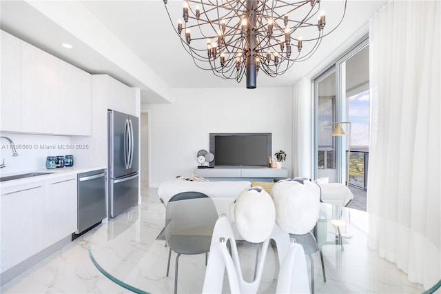 kitchen with a notable chandelier, decorative backsplash, sink, appliances with stainless steel finishes, and white cabinets