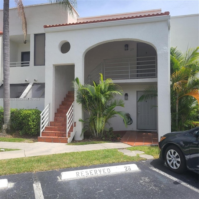 3564 Magellan Cir Unit 211-1, Aventura, FL 33180 - view of front of property with stairs, stucco siding, uncovered parking, a tiled roof, and a balcony