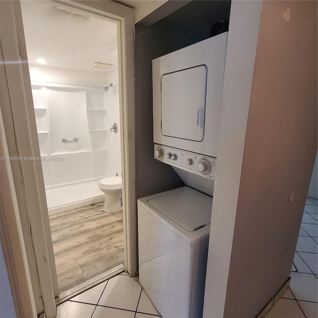 laundry area with light hardwood / wood-style floors and stacked washer / dryer