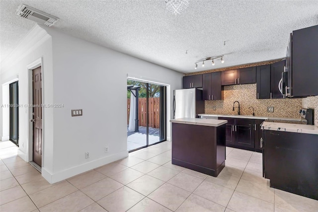 kitchen with appliances with stainless steel finishes, dark brown cabinets, a textured ceiling, sink, and a center island