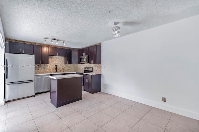 kitchen featuring a textured ceiling, a center island, dark brown cabinetry, and stainless steel appliances