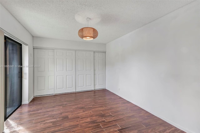 unfurnished bedroom with a closet, dark hardwood / wood-style flooring, and a textured ceiling