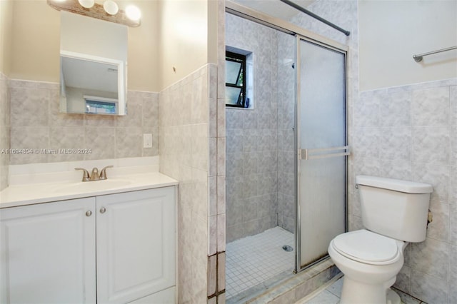 bathroom featuring vanity, toilet, tile walls, and a shower with shower door