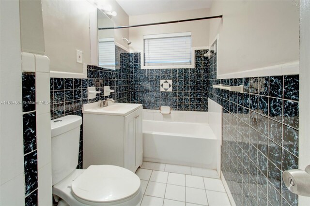 full bathroom featuring vanity, tile patterned floors, tiled shower / bath, toilet, and tile walls