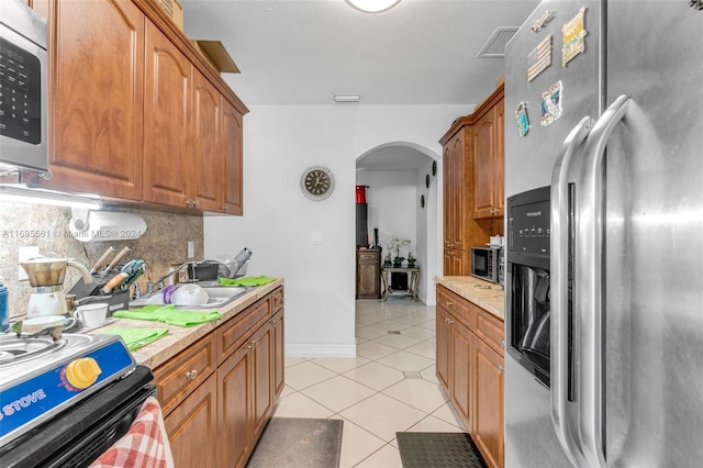 kitchen with decorative backsplash, light tile patterned flooring, sink, and stainless steel appliances