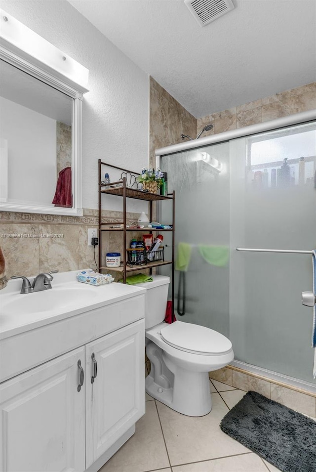 bathroom with tile patterned floors, an enclosed shower, a textured ceiling, vanity, and toilet