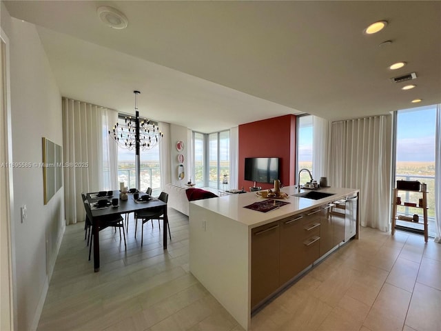 kitchen with sink, hanging light fixtures, a kitchen island with sink, a chandelier, and stainless steel dishwasher