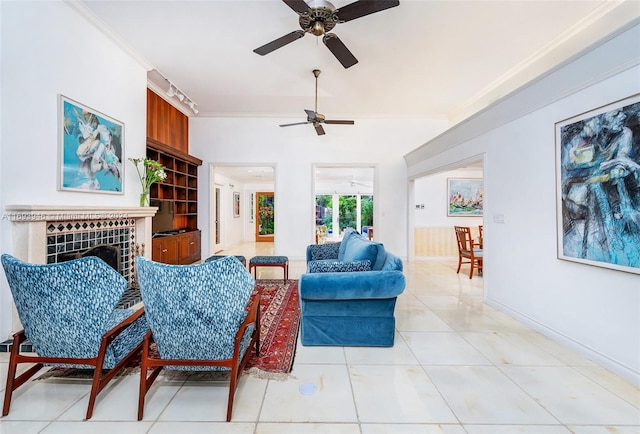 living room with ceiling fan, light tile patterned floors, crown molding, and a tile fireplace