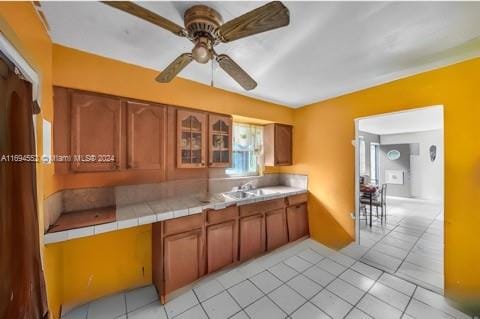 kitchen featuring light tile patterned floors, tile countertops, ceiling fan, and sink