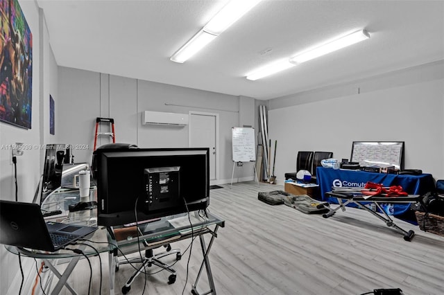 office with light wood-type flooring, a textured ceiling, and a wall mounted AC