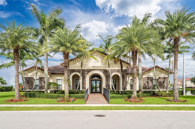 mediterranean / spanish-style house featuring french doors and a front lawn