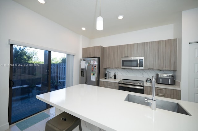 kitchen featuring sink, stainless steel appliances, pendant lighting, a kitchen bar, and light tile patterned floors