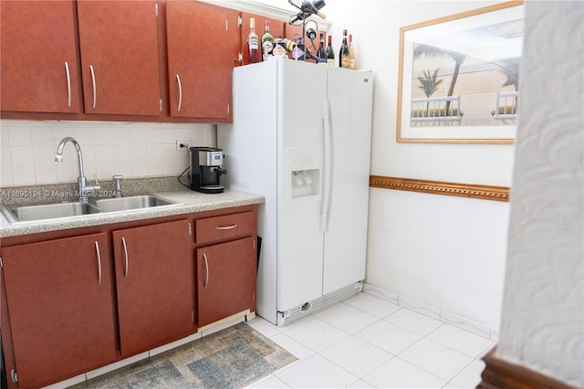 kitchen with light tile patterned floors, white refrigerator with ice dispenser, sink, and backsplash