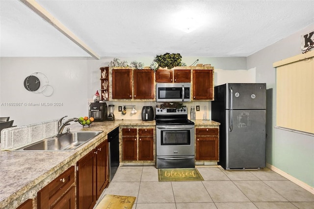 kitchen with a textured ceiling, light tile patterned flooring, sink, and appliances with stainless steel finishes