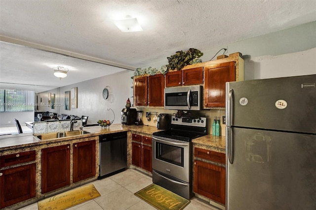 kitchen with kitchen peninsula, appliances with stainless steel finishes, tasteful backsplash, sink, and light tile patterned floors