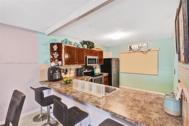 kitchen featuring a textured ceiling, appliances with stainless steel finishes, tasteful backsplash, beam ceiling, and kitchen peninsula