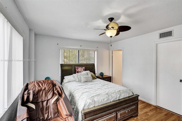 bedroom with ceiling fan, light hardwood / wood-style floors, and a textured ceiling