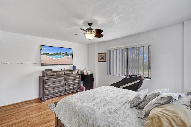 bedroom with ceiling fan, light hardwood / wood-style flooring, and a textured ceiling