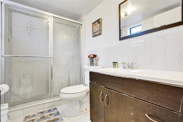 bathroom with tile patterned flooring, toilet, a shower with door, vanity, and tile walls