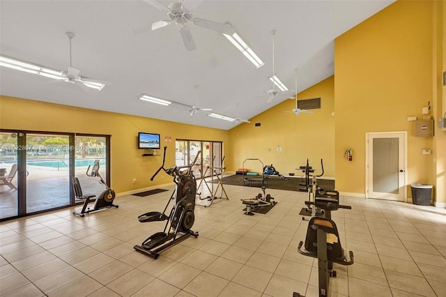 exercise room featuring ceiling fan, light tile patterned floors, and vaulted ceiling