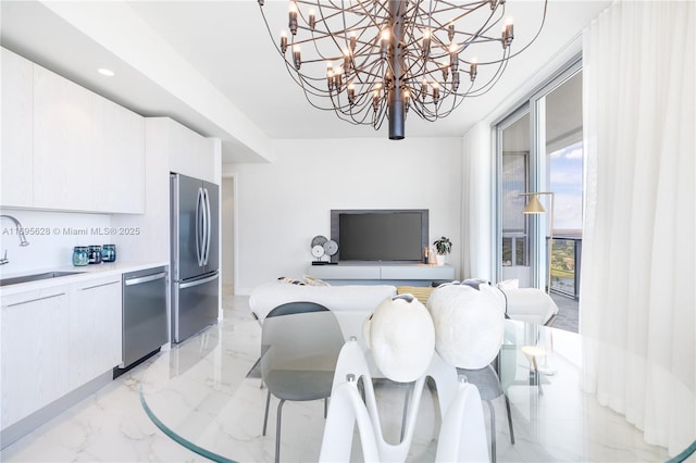 kitchen featuring appliances with stainless steel finishes, decorative backsplash, a chandelier, white cabinets, and sink