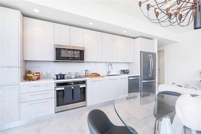 kitchen featuring sink, white cabinetry, appliances with stainless steel finishes, and hanging light fixtures