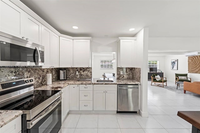 kitchen with light stone countertops, stainless steel appliances, sink, white cabinets, and light tile patterned flooring