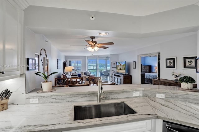 kitchen with white cabinets, light stone counters, and sink