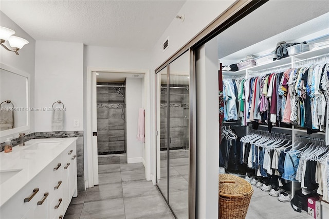 bathroom with vanity, a textured ceiling, an enclosed shower, and tile patterned flooring