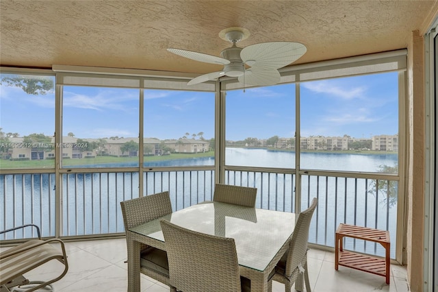 sunroom / solarium with ceiling fan, a healthy amount of sunlight, and a water view