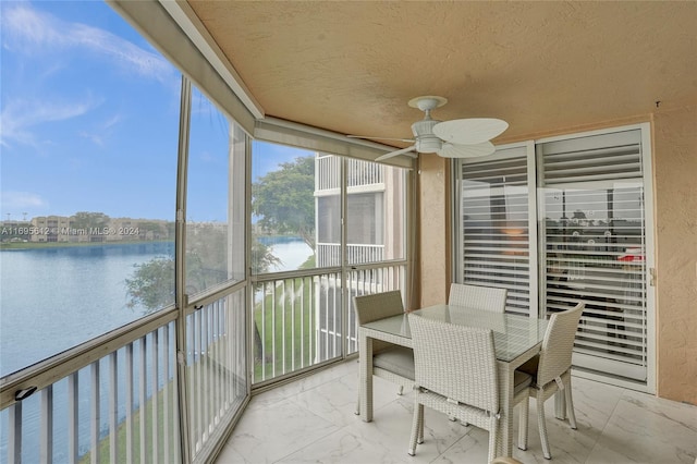 sunroom / solarium with ceiling fan and a water view