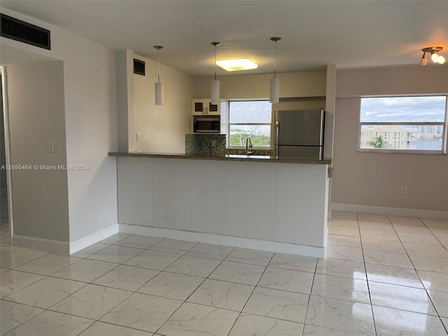 kitchen featuring pendant lighting, backsplash, sink, appliances with stainless steel finishes, and kitchen peninsula