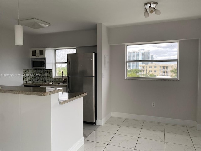 kitchen featuring kitchen peninsula, a wealth of natural light, stainless steel appliances, and tasteful backsplash