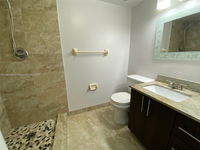 bathroom featuring a tile shower, vanity, and toilet