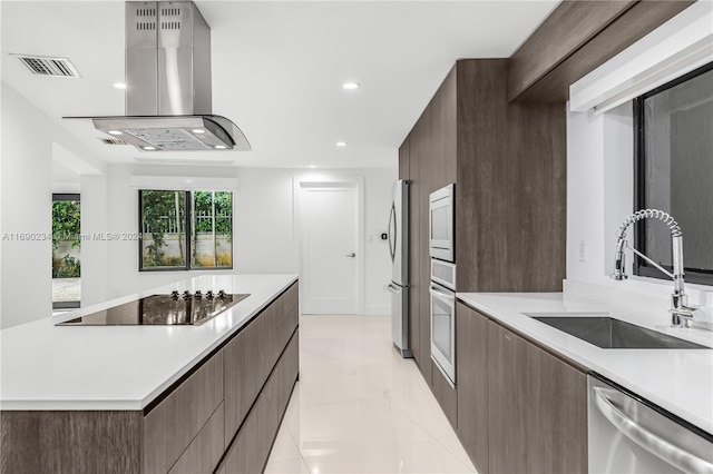 kitchen featuring dark brown cabinetry, wall chimney range hood, sink, and appliances with stainless steel finishes