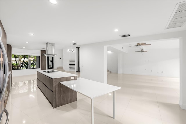 kitchen with black electric stovetop, a spacious island, ceiling fan, light tile patterned floors, and dark brown cabinetry