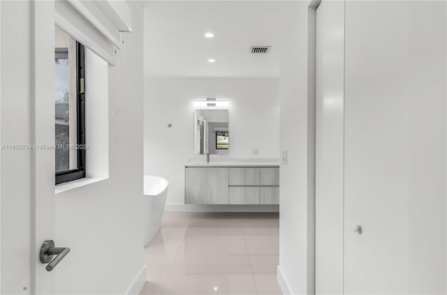 hallway with light tile patterned floors, a healthy amount of sunlight, and sink