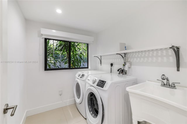 laundry area with light tile patterned floors, separate washer and dryer, and sink