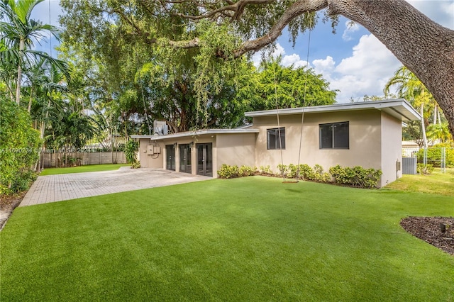 rear view of property with central air condition unit, a patio area, and a yard