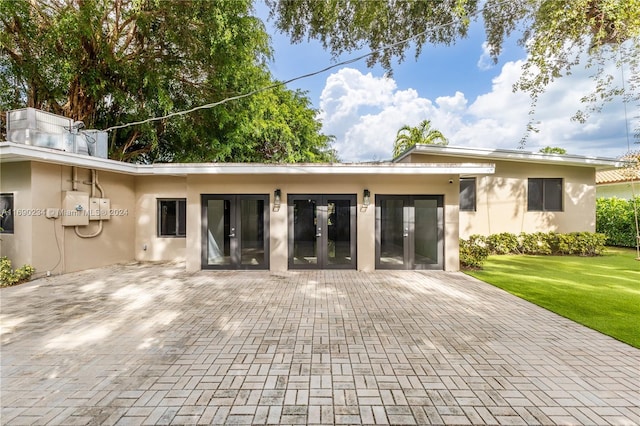 rear view of house with french doors, a patio area, and a lawn