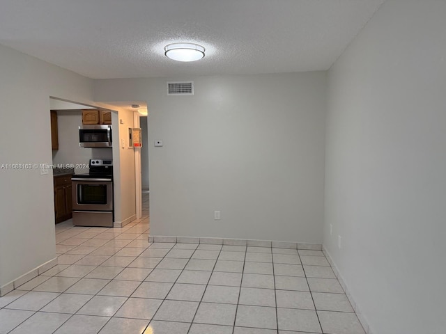 tiled empty room with a textured ceiling