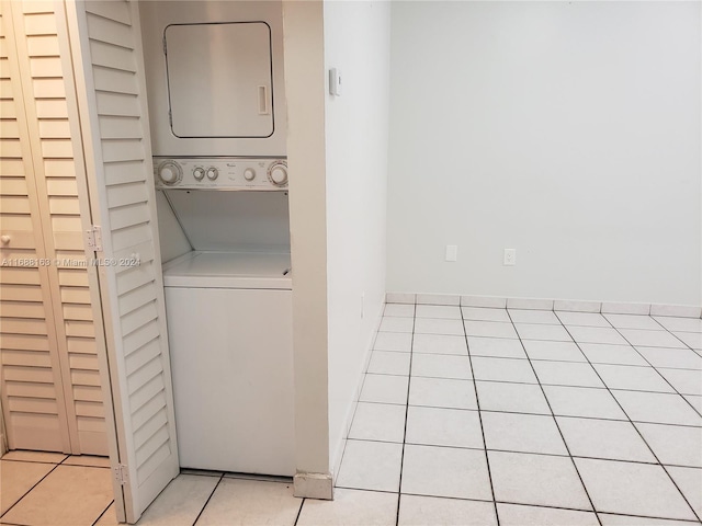 clothes washing area with light tile patterned floors and stacked washer / dryer