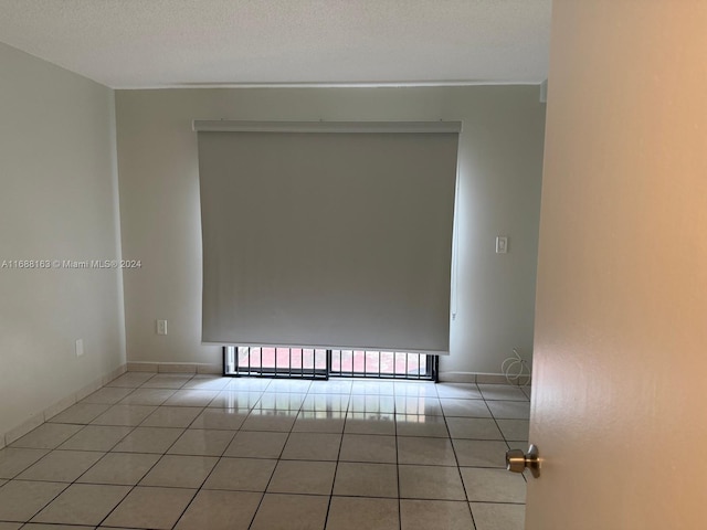 tiled spare room featuring a textured ceiling