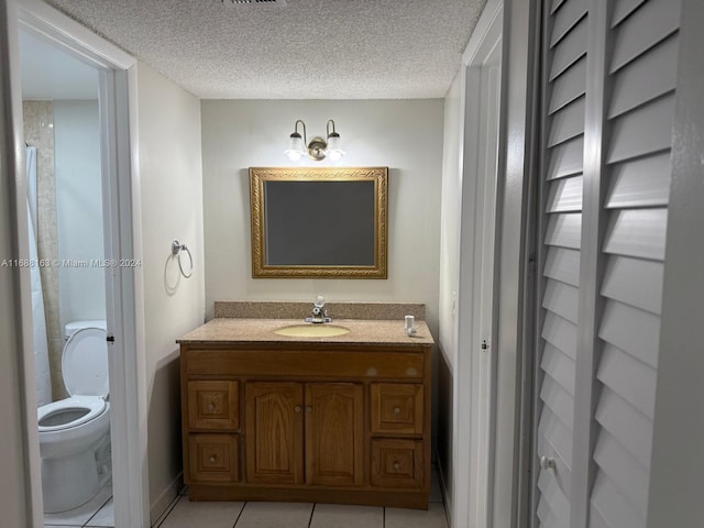 bathroom with tile patterned floors, vanity, a textured ceiling, and toilet