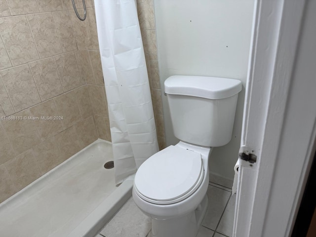 bathroom with a shower with shower curtain, toilet, and tile patterned floors