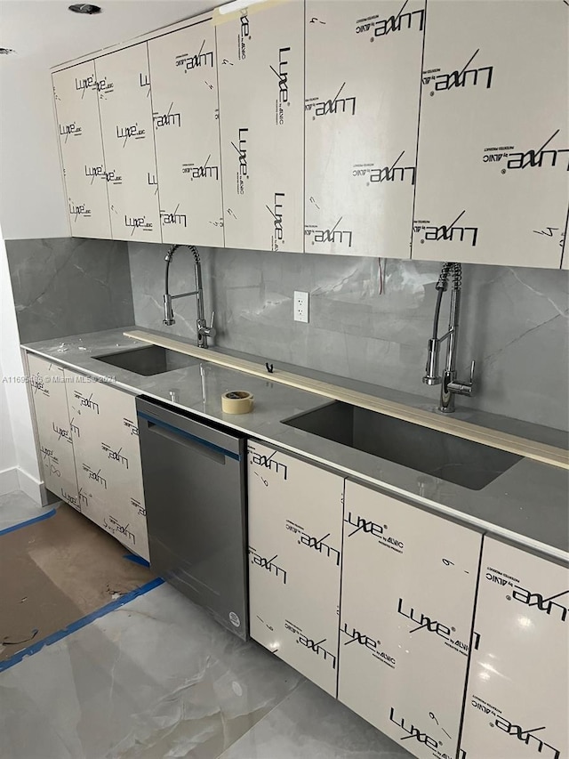 kitchen featuring decorative backsplash, white cabinets, dishwasher, and sink