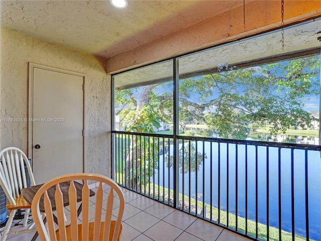 sunroom featuring a water view