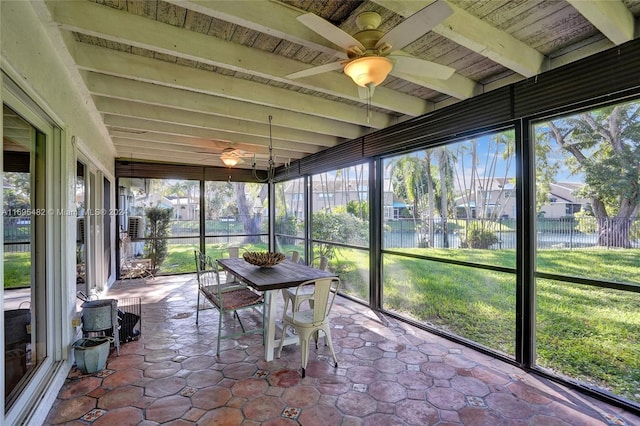 unfurnished sunroom featuring beamed ceiling, ceiling fan, a water view, and a wealth of natural light